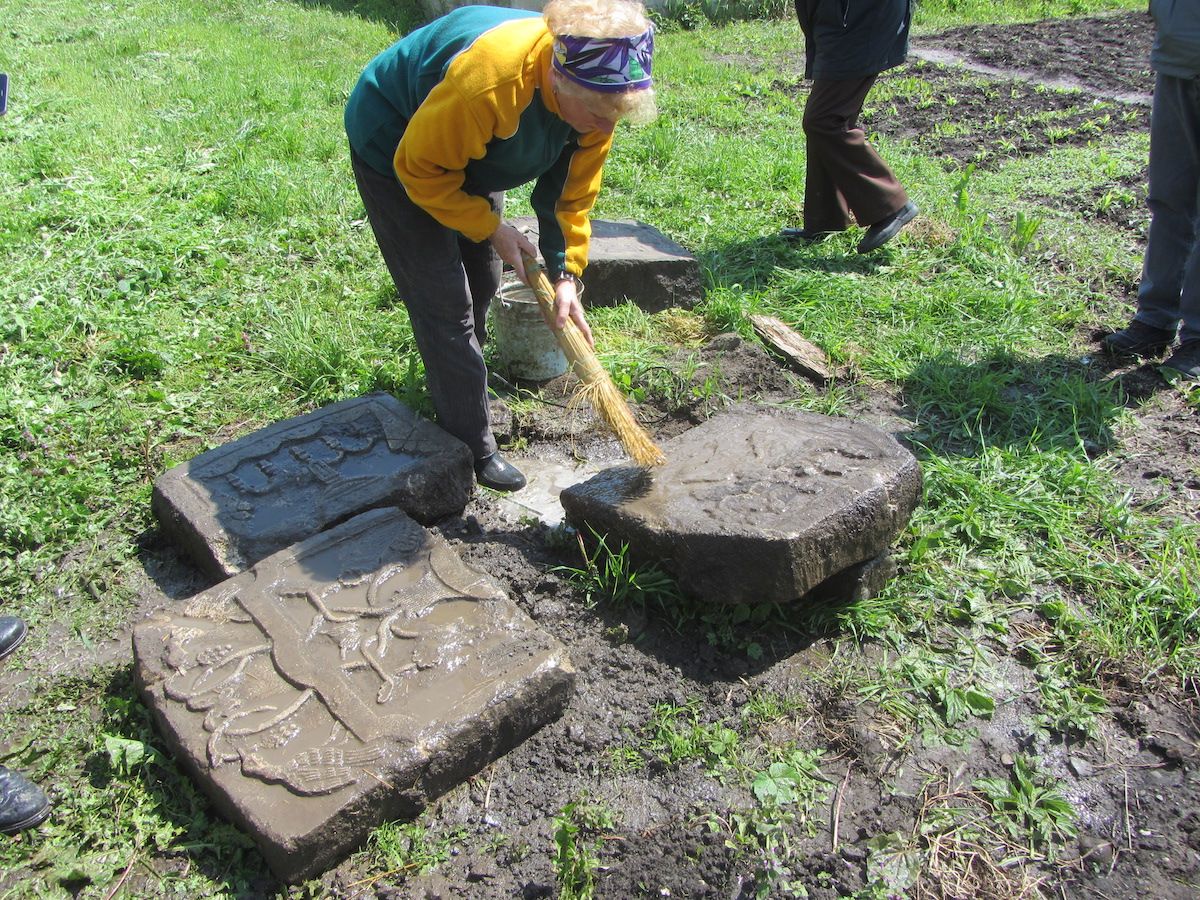 Жительница Рогатина расчищает фрагменты еврейских надгробий, найденных у нее в саду - фото 59092