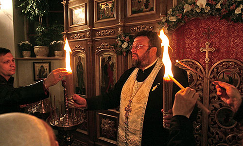 Священик Олександр Білокур роздає Благодатний вогонь своїй пастві