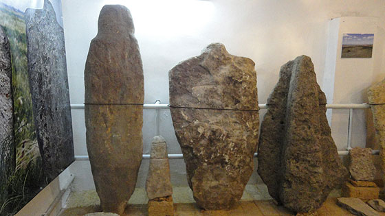 Фалоїдний камінь (ліворуч) та людиноподібна стела (в центрі) епохи міді-бронзи і кіммерійська скульптура (праворуч)